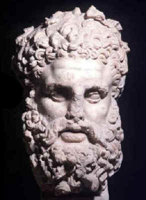 Testa in marmo che raffigura Ercole con folti capelli e una lunga barba. Alloggiato al Museo del Bardo (sala 23), proviene da Gightis