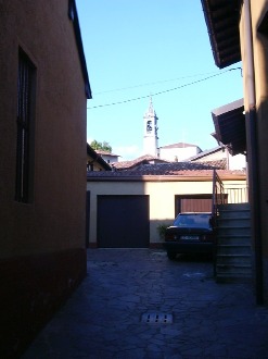 Il campanile e la chiesa visti da una corte del prestino in centro paese lungo via S. Agostino