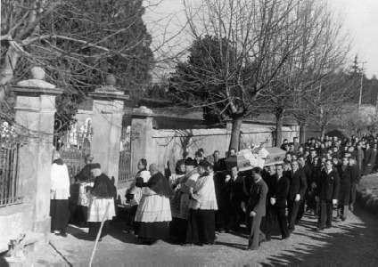 La bara di don Enrico Colnaghi, portata a spalla, sta per entrare attraverso il vecchio cancello del cimitero