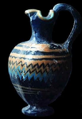 Oinochoe in pasta di vetro a becco trilobato con una decorazione geometrica policroma. Proviene dalla necropoli di Cartagine. Risale al VI-V sec. a. C. E' conservata al Museo del Bardo.