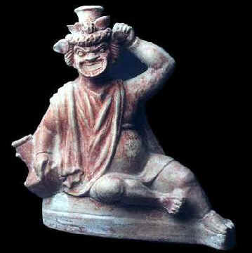 Vaso in terracotta che raffigura un attore comico con il viso mascherato. Steso per terra, con gli attributi bacchici, sembra interpretare il ruolo dell'ubriaco
